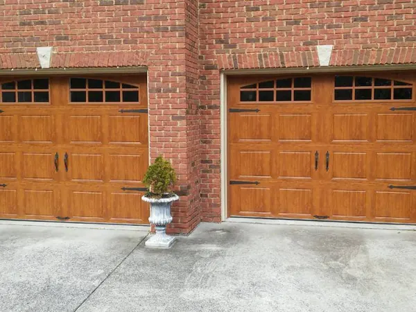 Two wood-grain doors with arched windows on a red brick house