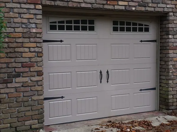 A tan carriage-style door with arched windows set in old brick