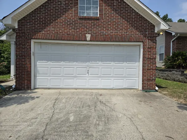A white raised-panel double door on a red brick garage