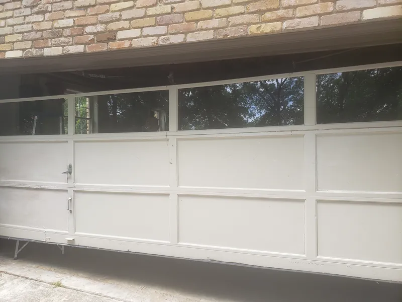 A white panel garage door with a row of windows